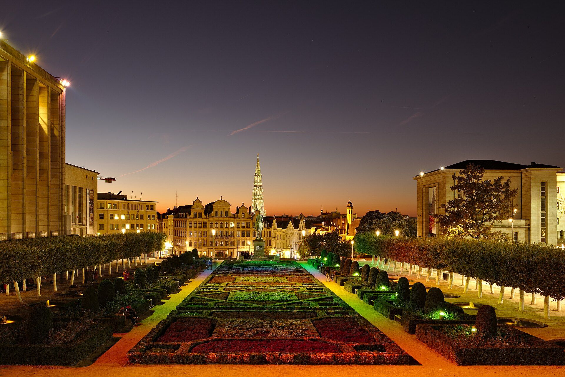 Le jardin du Mont des Arts à Bruxelles au crépuscule, avec la flèche de l'hôtel de ville au loin