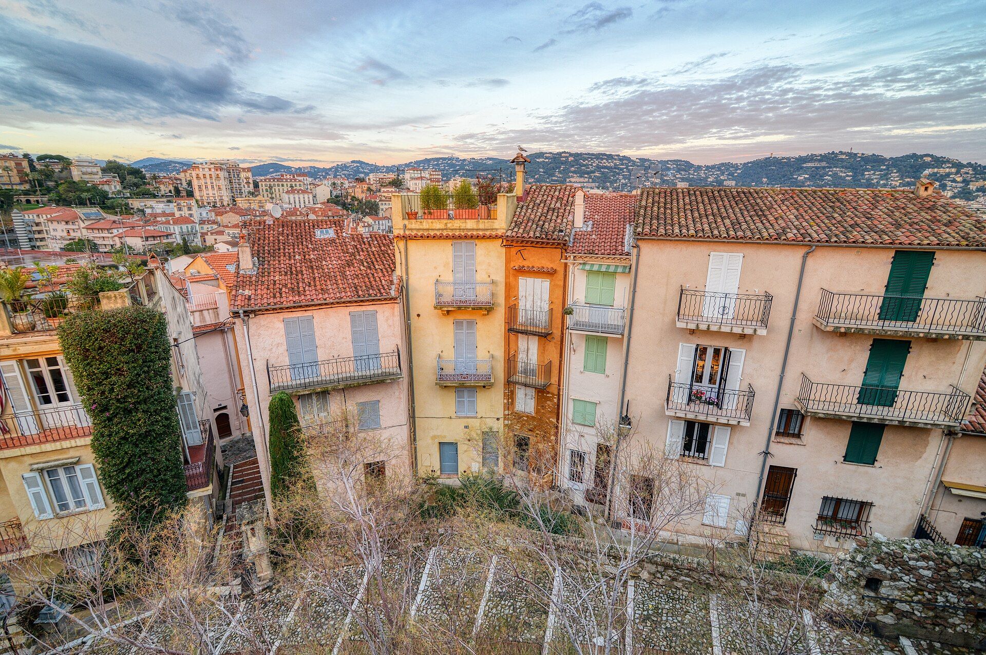 Façades colorées aux volets verts et toits de tuiles du Suquet, la vieille ville de Cannes, avec les collines en arrière-plan